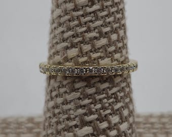 May include: A gold band ring with a row of small clear stones.