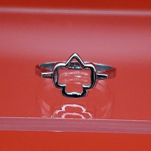May include: A silver ring with a cutout design in the shape of a four-leaf clover.