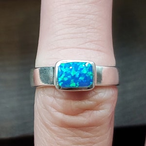 May include: A silver ring with a blue and green opal gemstone.