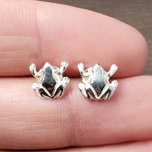 May include: A pair of silver frog stud earrings. The frogs are facing forward with their legs outstretched.