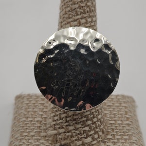 May include: A silver hammered ring with a large, round face.