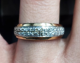 May include: A gold and silver ring with a band of small, round stones.