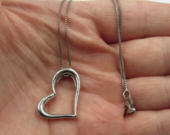 May include: A silver chain necklace with a silver open heart pendant.