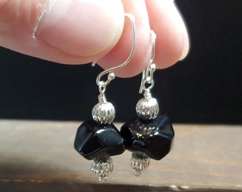 May include: Black glass bead earrings with silver accents and a silver hook closure.