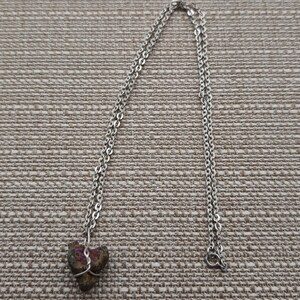 May include: A silver chain necklace with a small, heart-shaped, iridescent gemstone pendant.