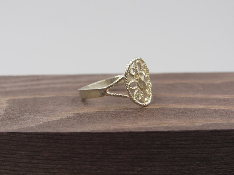 May include: A silver filigree ring with a delicate, openwork design. The ring is oval-shaped and has a smooth, polished finish.