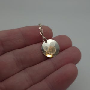 May include: A silver necklace with a round pendant featuring a Mickey Mouse silhouette.