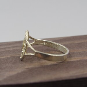 May include: Silver ring with a delicate, intricate design. The ring is marked with the number "925" on the inside band, indicating it is made of sterling silver.
