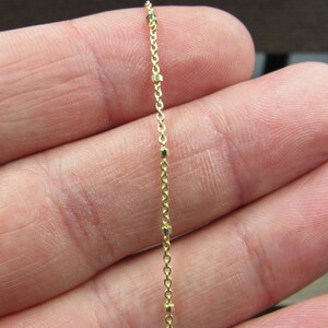 May include: A gold chain necklace with small round beads. The chain is delicate and has a subtle shine.