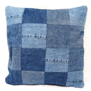 Peut inclure: Une housse de coussin en jean bleu avec un motif patchwork. La housse de coussin est faite de différentes nuances de jean bleu et est cousue ensemble en un motif de grille.