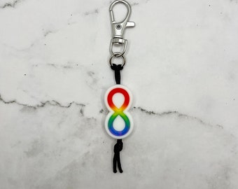 May include: A rainbow infinity symbol keychain with a black cord and a silver clip.