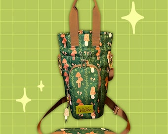 May include: A brown and green canvas tote bag with a mushroom print. The bag has a zippered pocket on the front and a brown leather strap. The bag is made by the company "ArteXan".