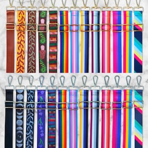 May include: A selection of patterned bag straps with gold-coloured metal clasps. Designs include floral, geometric, and striped patterns in various colours such as brown, purple, blue, pink, and rainbow. Each strap has a metal clasp for easy attachment.