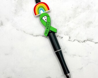 May include: Black pen with a green ribbon charm that says "You Matter" and a rainbow charm.