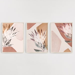 May include: Three framed prints with a watercolor design of protea flowers in shades of pink, brown, and white on a light pink background.