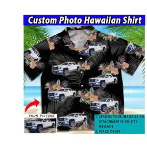 May include: A black Hawaiian shirt with a white truck pattern. The shirt has a button-up collar and short sleeves. The image shows instructions for customizing the shirt with a personal photo.
