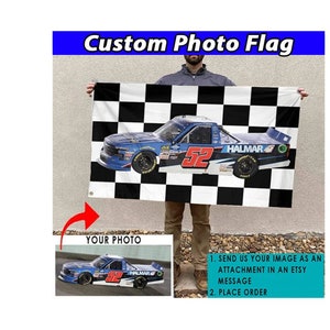 May include: A custom photo flag with a checkered black and white background. A blue race truck with the number 52 and the word "HALMAR" is printed on the flag. The flag is held by a person.
