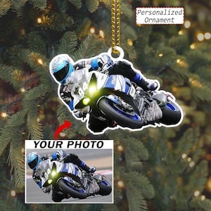 May include: A personalized ornament featuring a motorcycle racer in a blue and white racing suit and helmet riding a blue and white sportbike with the number 94. The ornament includes a gold hanging string and the text Personalized Ornament.