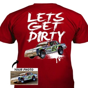 May include: Red t-shirt with the words "LETS GET DIRTY" in white brush lettering. A race car graphic is below the text, with the number 67 on the side. A smaller image of the race car is in the lower left corner.