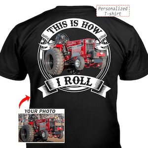 Op de afbeelding: Zwart T-shirt met een rode tractorafbeelding en de tekst "THIS IS HOW I ROLL". Het ontwerp bevat een foto van een tractor en de woorden "Personalized T-shirt".