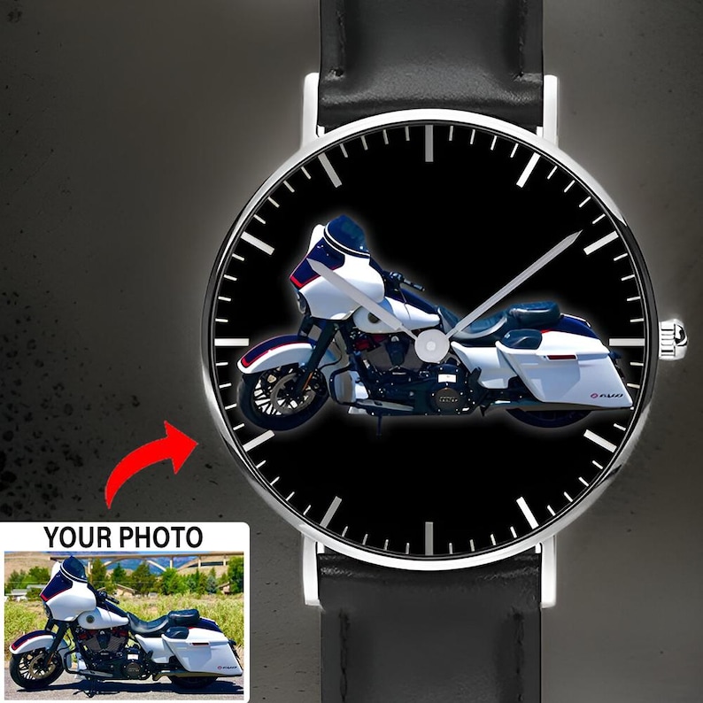 May include: A wristwatch with a black leather strap and a round silver case. The watch face features a black background with white hour markers and a graphic of a white motorcycle with blue and red accents. A small inset shows the original photo.