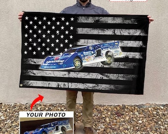 Może przedstawiać: Czarna flaga z postarzanym wzorem amerykańskiej flagi i niebieską grafiką samochodu wyścigowego. Flaga zawiera tekst "Personalized Flag" i "YOUR PHOTO" ze zdjęciem samochodu wyścigowego.