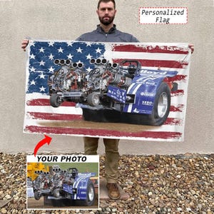 Könnte beinhalten: Eine rechteckige Flagge mit einem abgenutzten amerikanischen Flaggendesign als Hintergrund und einer großen, detaillierten Grafik eines blauen Traktors mit zwei Motoren. Der Text Personalized Flag steht oben rechts.
