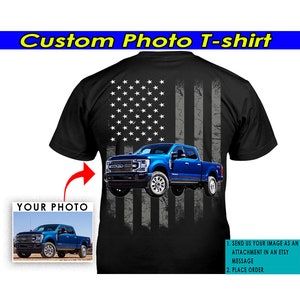 May include: A black t-shirt with a blue pickup truck in front of an American flag design. The truck is superimposed over the flag. The t-shirt is customizable with a photo of your own truck. Instructions for customizing the t-shirt are included.
