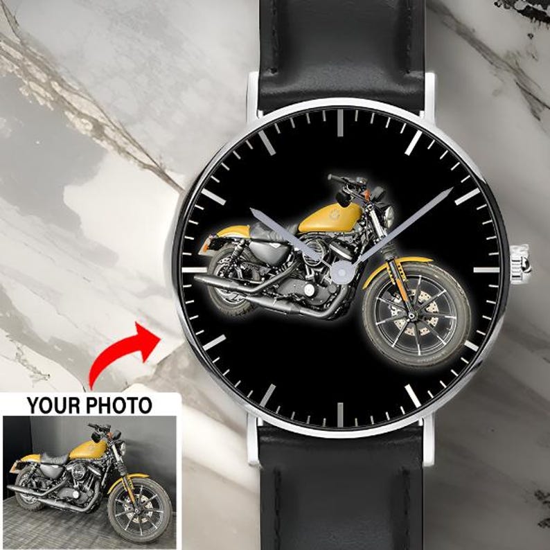 May include: A wristwatch with a black leather strap and a silver-toned circular case. The watch face features a black background with a yellow motorcycle graphic in the center, white hour markers, and silver hands. A small inset shows the motorcycle.
