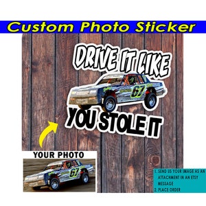 May include: Custom photo sticker with a race car and the text "DRIVE IT LIKE YOU STOLE IT".  The sticker is on a wood background.  The sticker is available for purchase and you can upload your own photo to be included in the sticker.