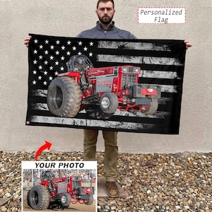 May include: A black flag featuring a distressed American flag design with a red tractor overlay. The tractor has large tires and the text "Hursting" is visible. The flag also has the text "Personalized Flag".