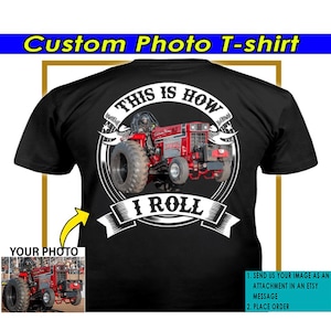 May include: A black t-shirt with a white graphic of a red tractor pulling a weight. The graphic includes the text "This is how I roll". The t-shirt is customizable with a photo of your own tractor.