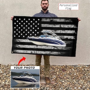 Op de afbeelding: Een rechthoekige vlag met een verweerd zwart-wit Amerikaans vlagontwerp en een op maat gemaakte afbeelding van een blauw-witte motorboot in het midden. De vlag is voorzien van metalen ringen om op te hangen en bevat de tekst Personalized Flag.