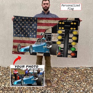 May include: A rectangular personalized flag featuring a blue dragster race car and a vertical drag racing Christmas tree light sequence set against a distressed American flag background. The design includes a smaller inset photo of a blue dragster.