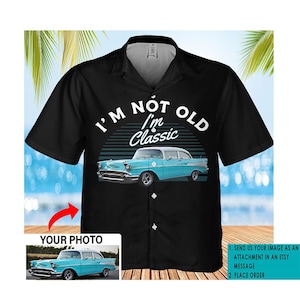 May include: A black button-up shirt with a vintage car graphic and the text "I'M NOT OLD I'm Classic". The shirt has a white collar and short sleeves. A blue car is shown in the graphic. The shirt is customizable with a photo of a car.