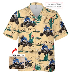 Könnte beinhalten: Kurzärmeliges, geknöpftes Hawaiihemd mit Wüstenmuster. Das Hemd hat ein sich wiederholendes Design aus blauen ATVs, Kakteen und Bergen auf beigem Hintergrund. Der Text "Personalized Hawaiian Shirt" ist sichtbar.