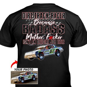 May include: Black t-shirt with the text "DIRT TRACK RACER Because BADASS Mother F*cker ISN'T AN OFFICIAL JOB TITLE". The shirt features a race car with the number 67. A smaller image of the race car is in the lower left corner.