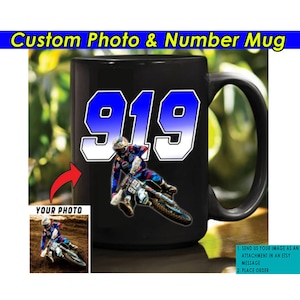 May include: Black ceramic mug featuring a motocross rider and the number 919 in blue and white. The mug includes the text "Custom Photo & Number Mug" and a small image of a rider. Instructions are included.