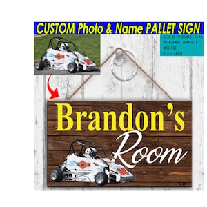 May include: A wooden sign with a brown woodgrain finish. The sign has a white rope hanger and says "Brandon's Room" in yellow and white lettering. A photo of a race car is in the bottom center of the sign.
