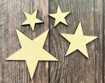 May include: Four wooden stars of varying sizes, arranged in a cluster on a brown wood background. The stars are a light brown colour.