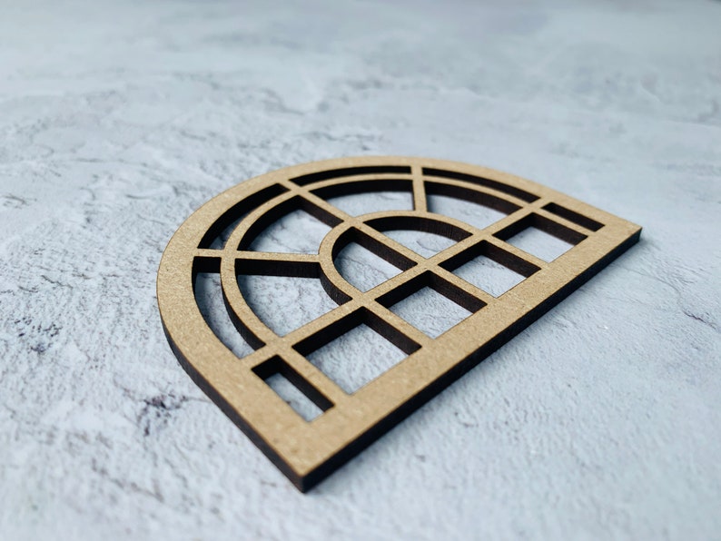 Op de afbeelding: Een houten uitsnijding van een halfronde venster met een geometrisch ontwerp. Het venster is gemaakt van meerdere vierkanten en rechthoeken.