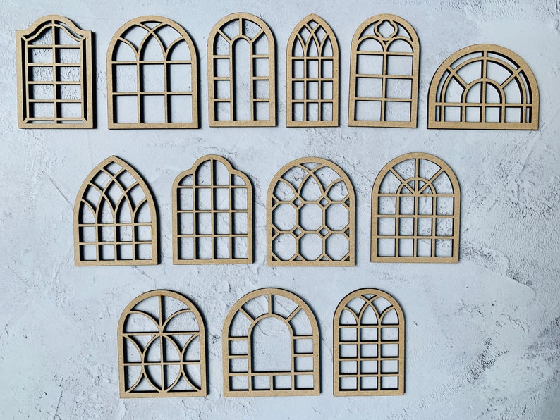Op de afbeelding: Een set van 15 houten boogvensterframes in verschillende stijlen en maten. De frames zijn gemaakt van onbehandeld hout en zijn perfect voor knutselprojecten.
