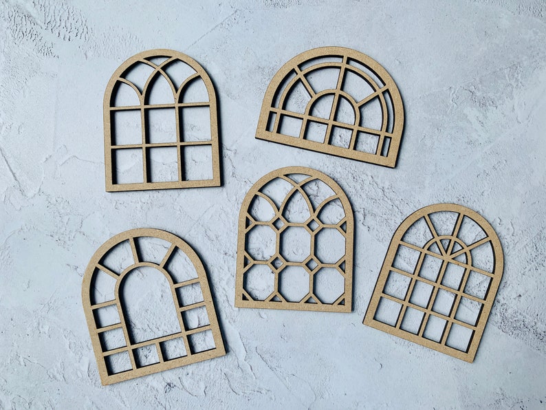 Op de afbeelding: Vijf houten boogvensterframes met verschillende ruitontwerpen. De frames zijn allemaal gemaakt van onbehandeld hout en hebben een natuurlijke bruine kleur.