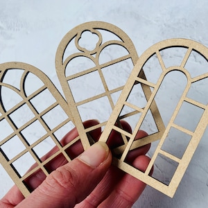 Op de afbeelding: Drie houten raamkozijnen met verschillende ontwerpen. De kozijnen zijn gemaakt van lichtbruin hout en hebben een verweerde afwerking. De kozijnen zijn perfect voor knutselprojecten, woonaccessoires of scrapbooking.