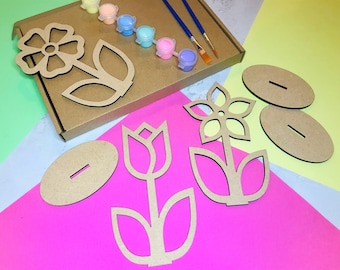 May include: A craft kit for painting wooden flower shapes. The kit includes three flower shapes, two round bases, paint pots, and paintbrushes.