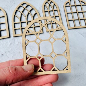 Op de afbeelding: Set van vijf houten boogvenster-uitsnijdingen met verschillende geometrische patronen. De uitsnijdingen zijn gemaakt van natuurlijk hout en hebben een rustieke, vintage uitstraling.