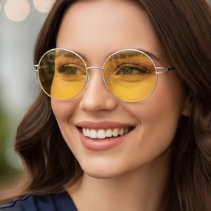 May include: Round sunglasses featuring thin silver metal frames and vibrant yellow tinted lenses. The circular lenses provide a clear view of the eyes, while the lightweight metallic structure connects at the bridge and extends to the temples.