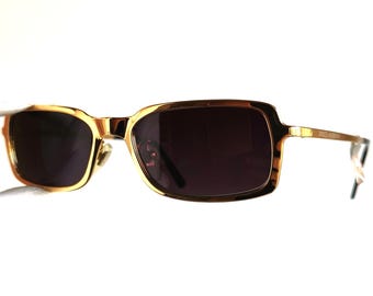 May include: Gold-tone rectangular sunglasses with dark lenses. The sunglasses have a thin metal frame.