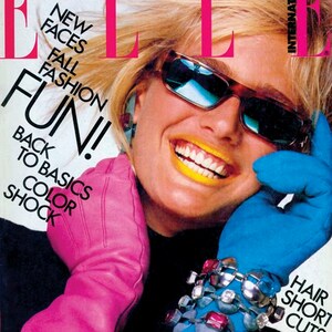 May include: A magazine cover featuring a woman wearing sunglasses and a pink glove. The magazine cover is for Elle International and features the text 'New Faces Fall Fashion Fun! Back to Basics Color Shock' and 'Hair Short Cuts'.
