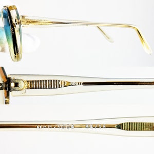 May include: Close-up of vintage gold-rimmed sunglasses with gradient blue and green lenses. The temples are clear with gold accents and the text "KP BRILLE" is visible. The frame size is 54/16.